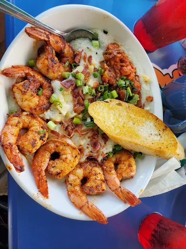 Grilled shrimp served over creamy grits with bacon and garlic bread at Sharkey’s.