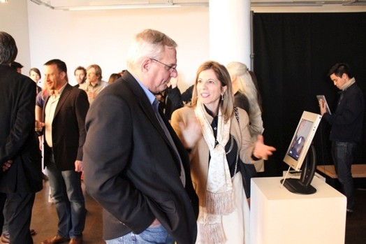 a woman is talking to an older man near a stand with an iPad