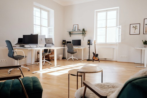 Ein Hell erlechteter und modern eingerichteter Workspace mit zwei weißen Fenstern