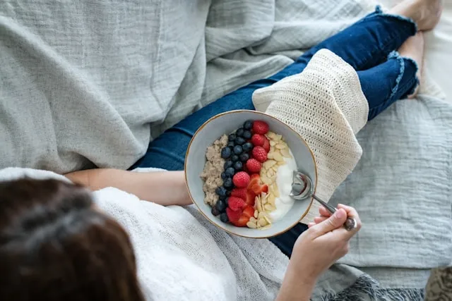 Bowl of yogurt and berries on a bed with a vitamin insight card overlay