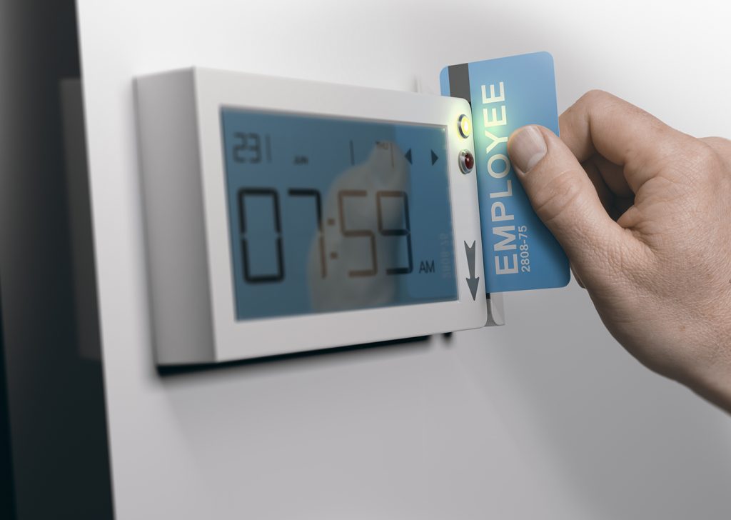 Una mano sta passando un badge fisico nel rilevatore presenze dipendenti per effettuare la timbratura, sul display compare l'orario della timbratura.
