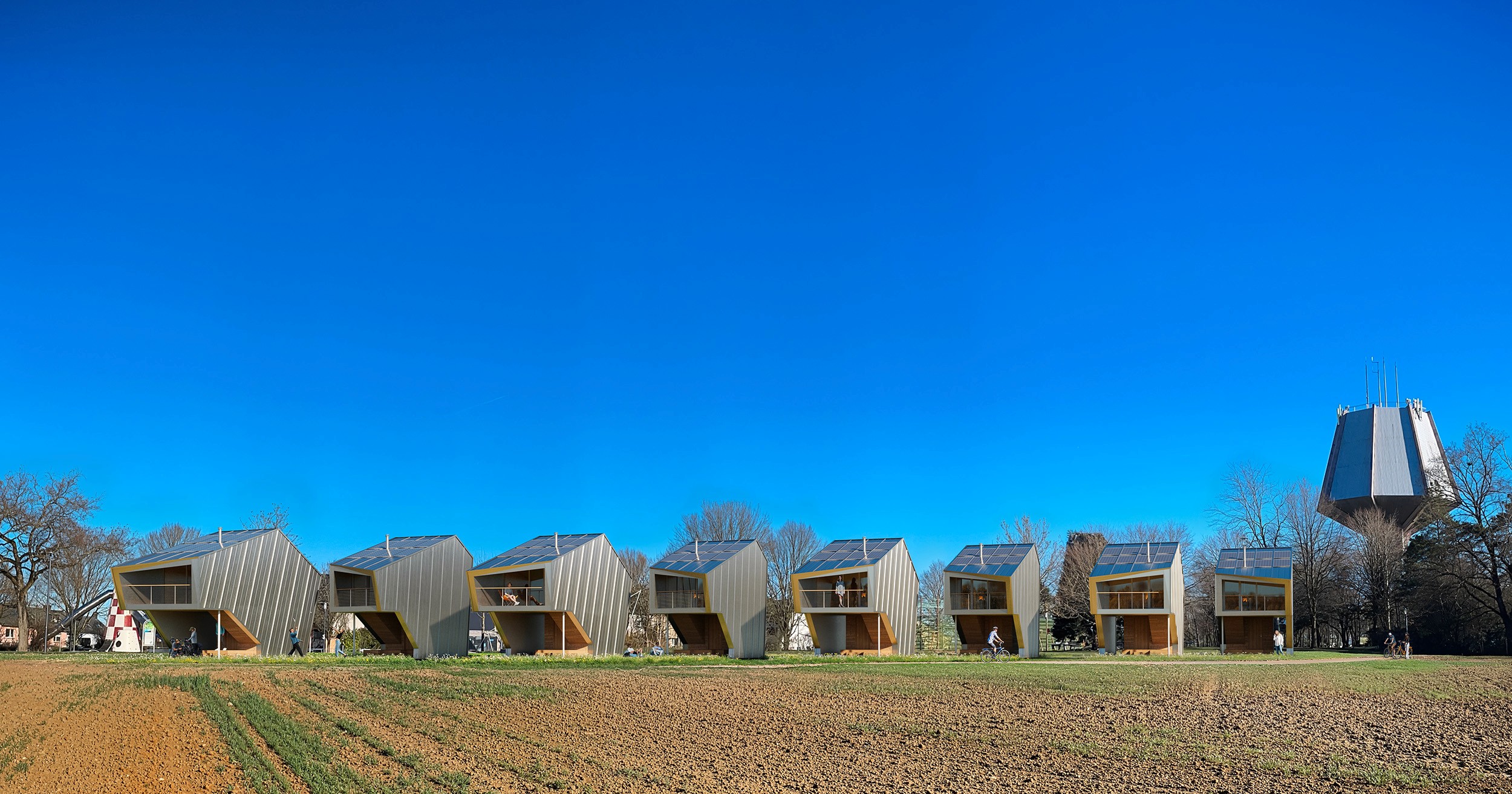 Rendering of Sideshore microhome community in Luxembourg countryside – sustainable prefabricated homes arranged in staggered pairs blending into farmland.