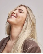 A model with straight blonde hair laughing.