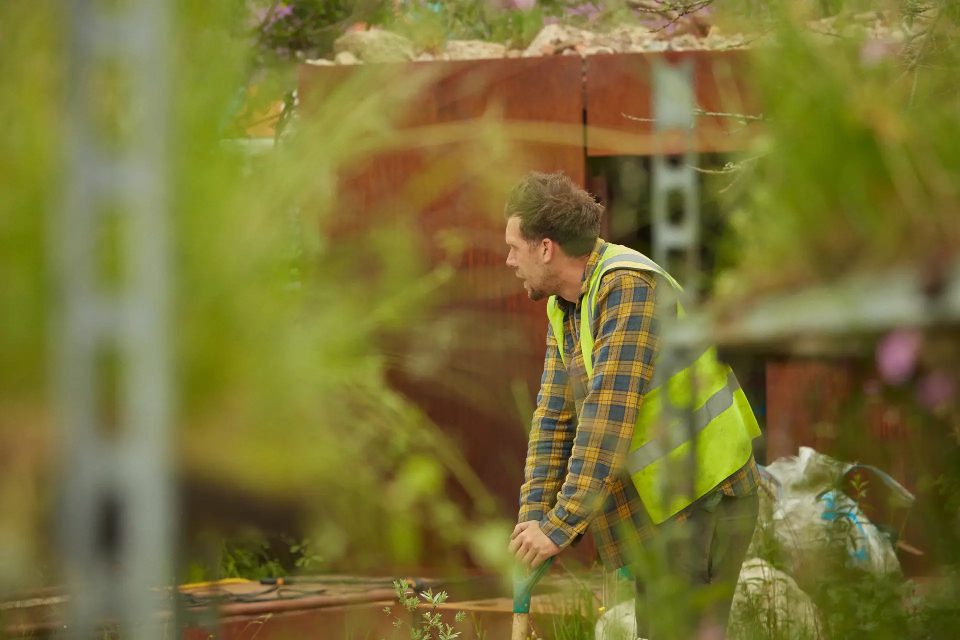 A close-up of a person tending to plants in a lush green environment, surrounded by vibrant foliage.