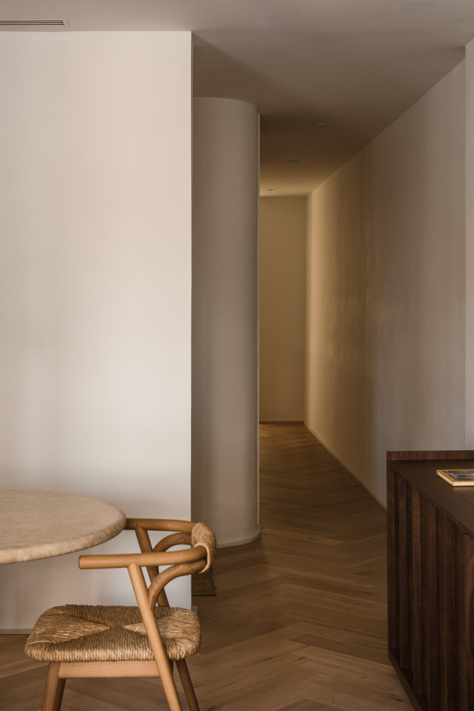 Curved hallway leading to the living spaces of a Madrid home by Atrato Estudio
