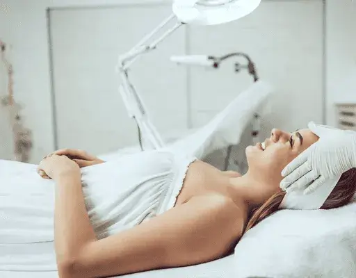 Woman relaxing during professional acne facial treatment to cleanse pores, calm skin, and reduce inflammation.