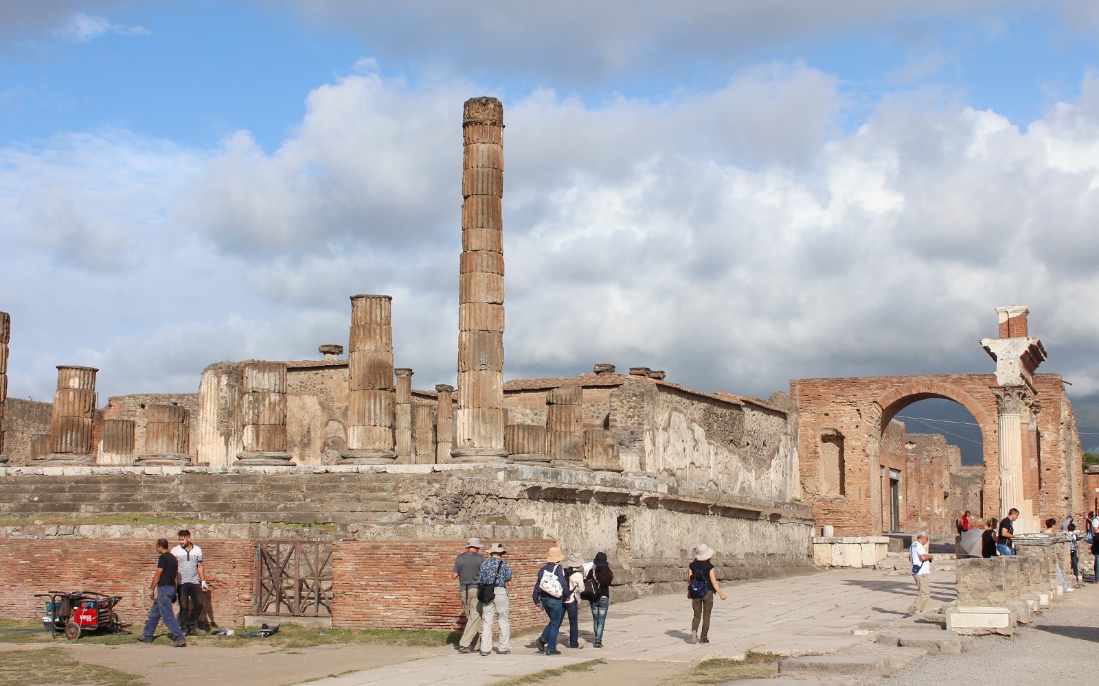 Visitors exploring ancient ruins with Mount Vesuvius in the background, Pompeii, Italy.