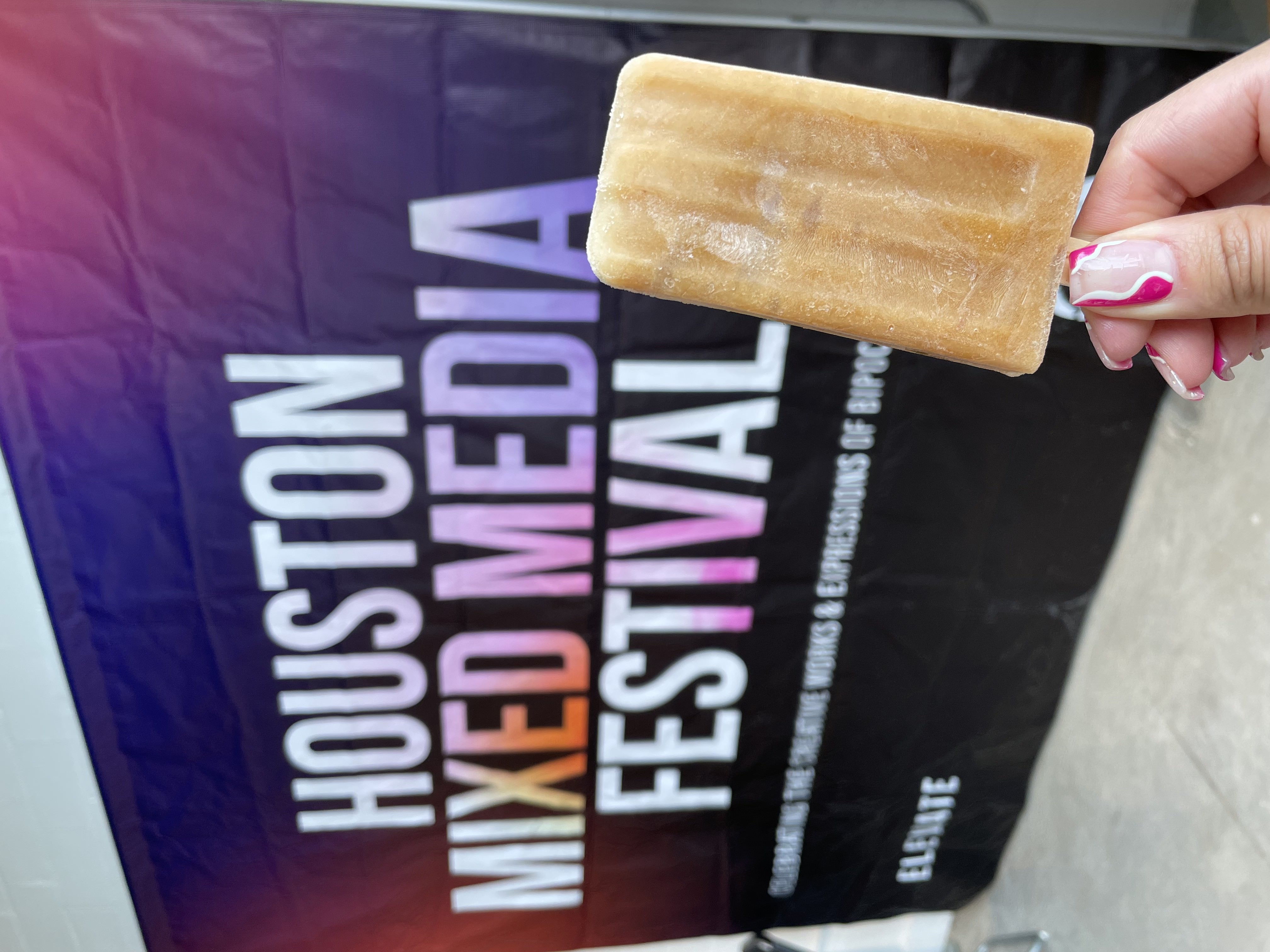 A while popsicle being held up in front of a Staples store location sign