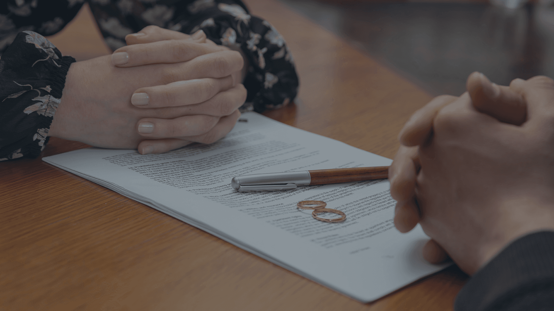Pen signing legal documents with wedding rings on the table, representing high net worth divorce proceedings at Lamb & Lamb, P.C. in Salem, MA