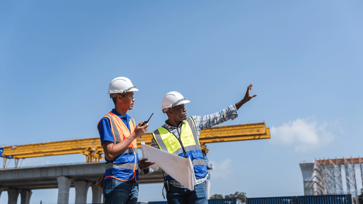 Site supervisors overseeing a heavy construction logistics operation with cranes in the background.