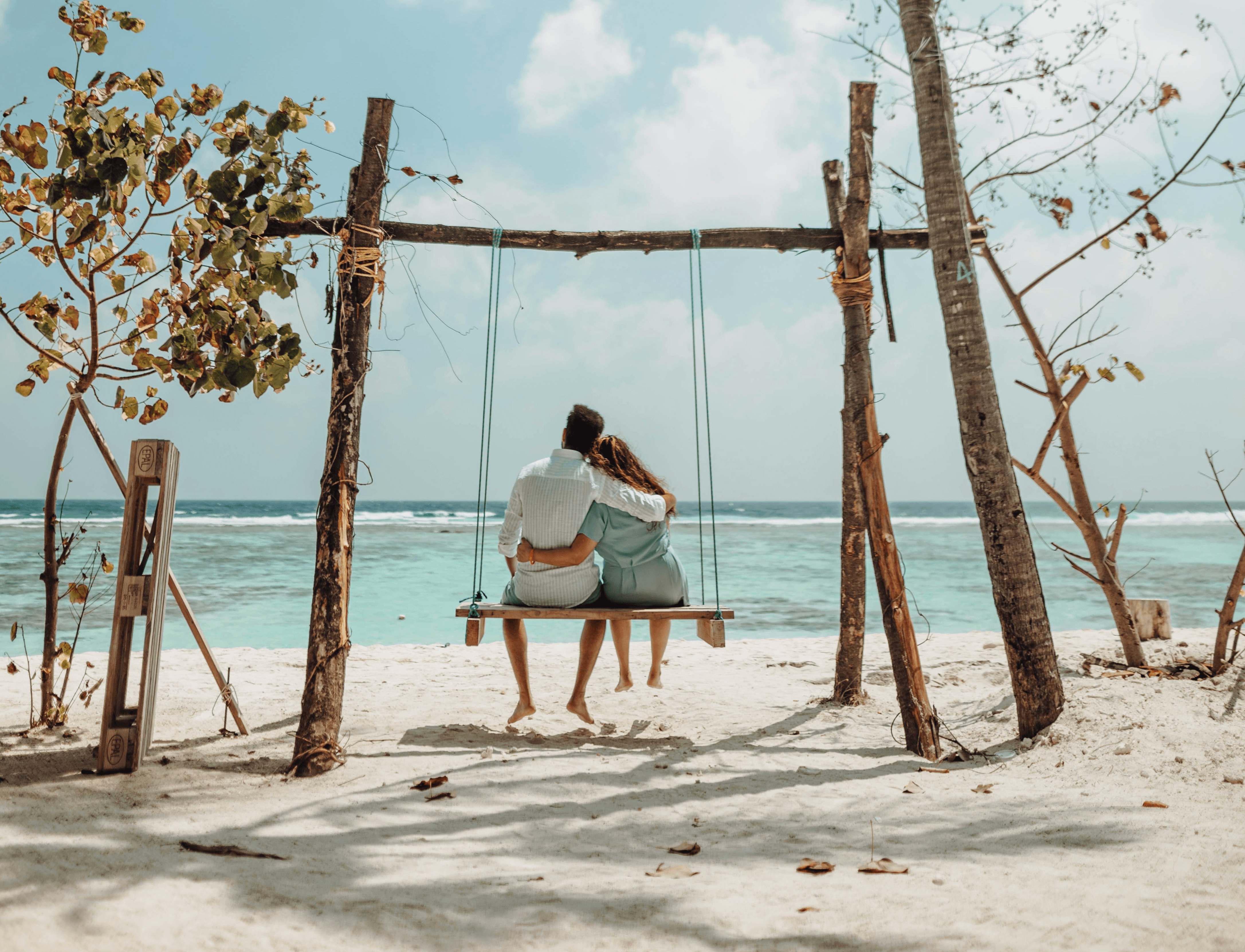 a couple sitting on a bench on a beach