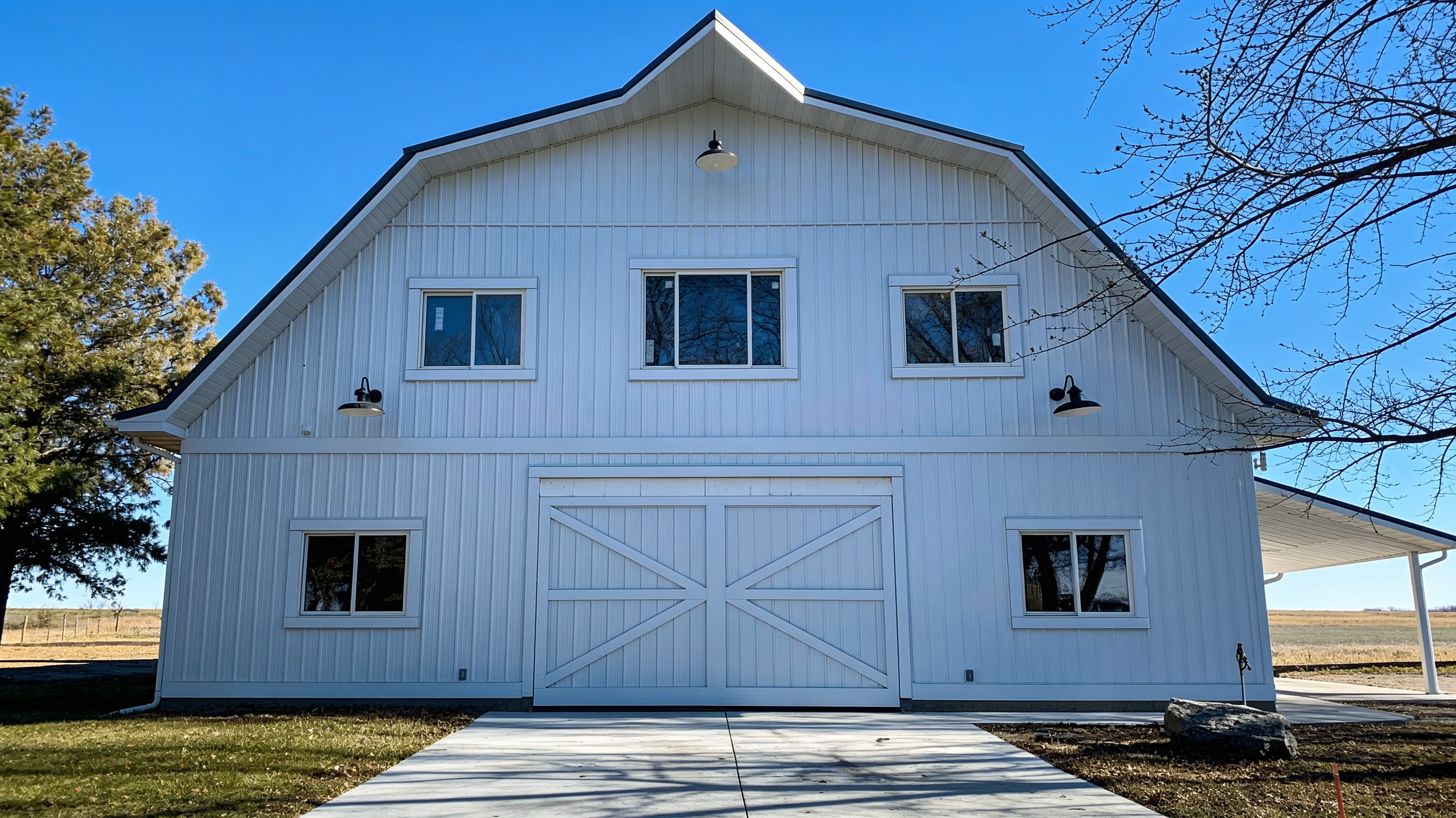 White barndominium with a closed 16x12 hydraulic agricultural door