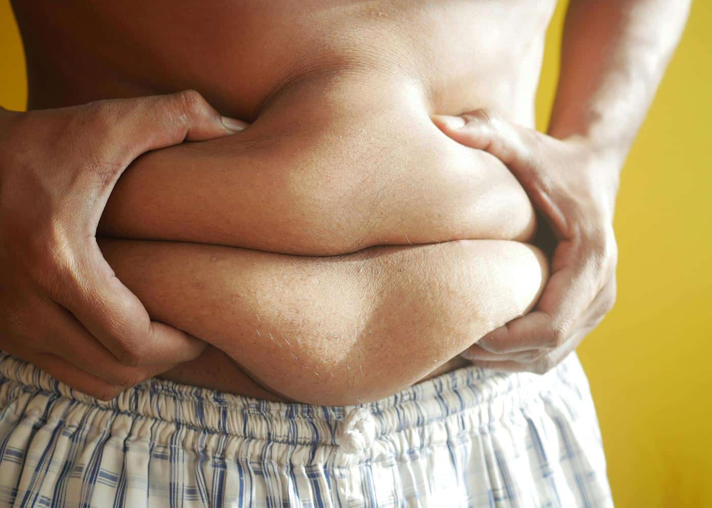 Person squeezing stomach to show fat