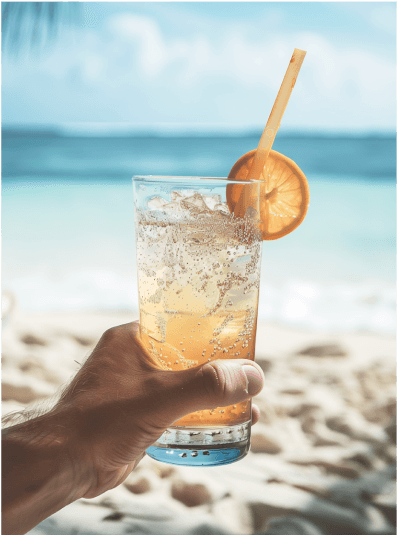 Lemon drinks and a woven basket with flowers set on a beach picnic by the sea.