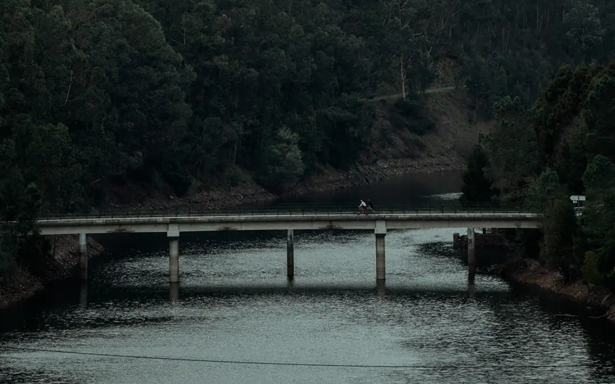 a cyclist riding a bridge on top of a river
