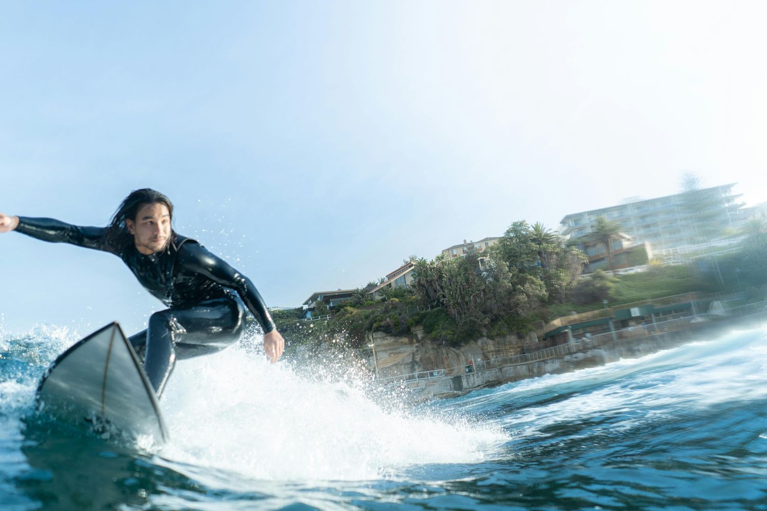 Surfer in a black wetsuit catching a wave in deep blue water — surfboard rental in East Asia