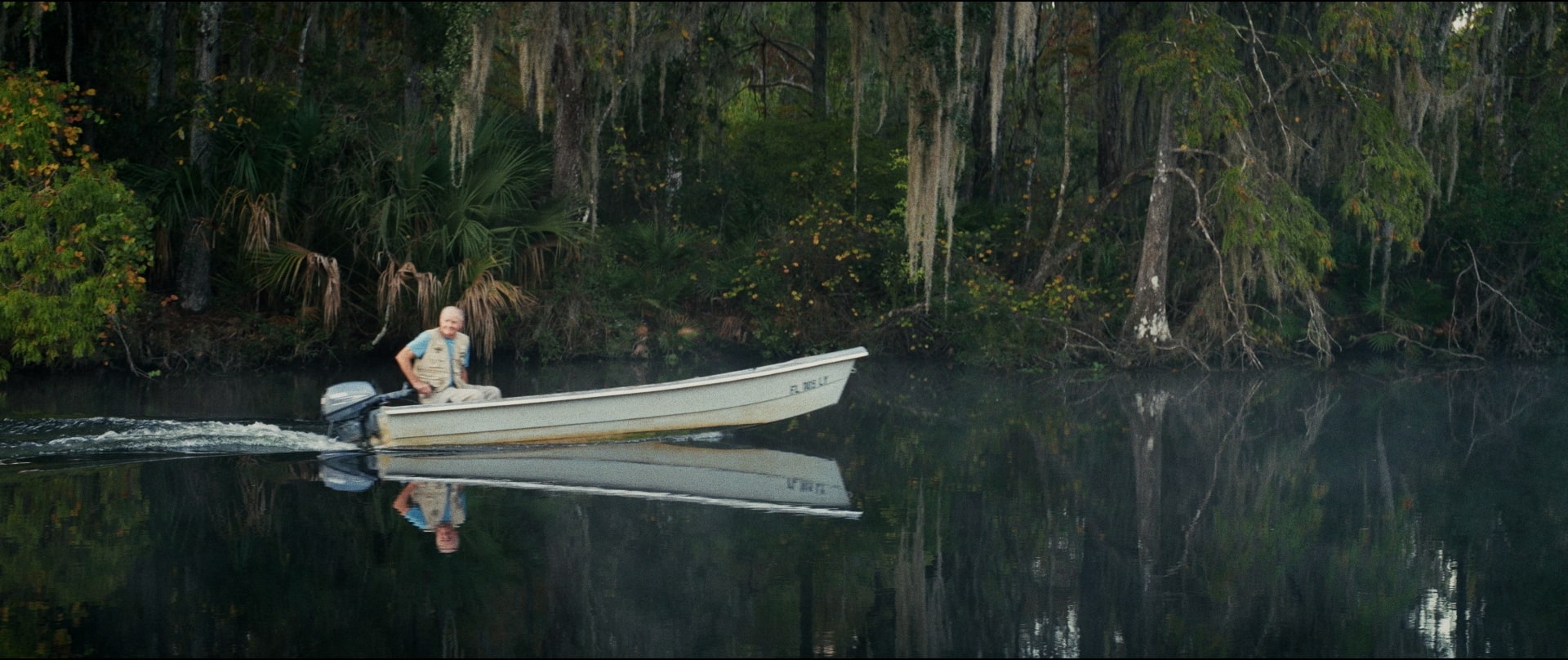 The front cover of a short film called in the current. The image shows an old man on a river in a boat.