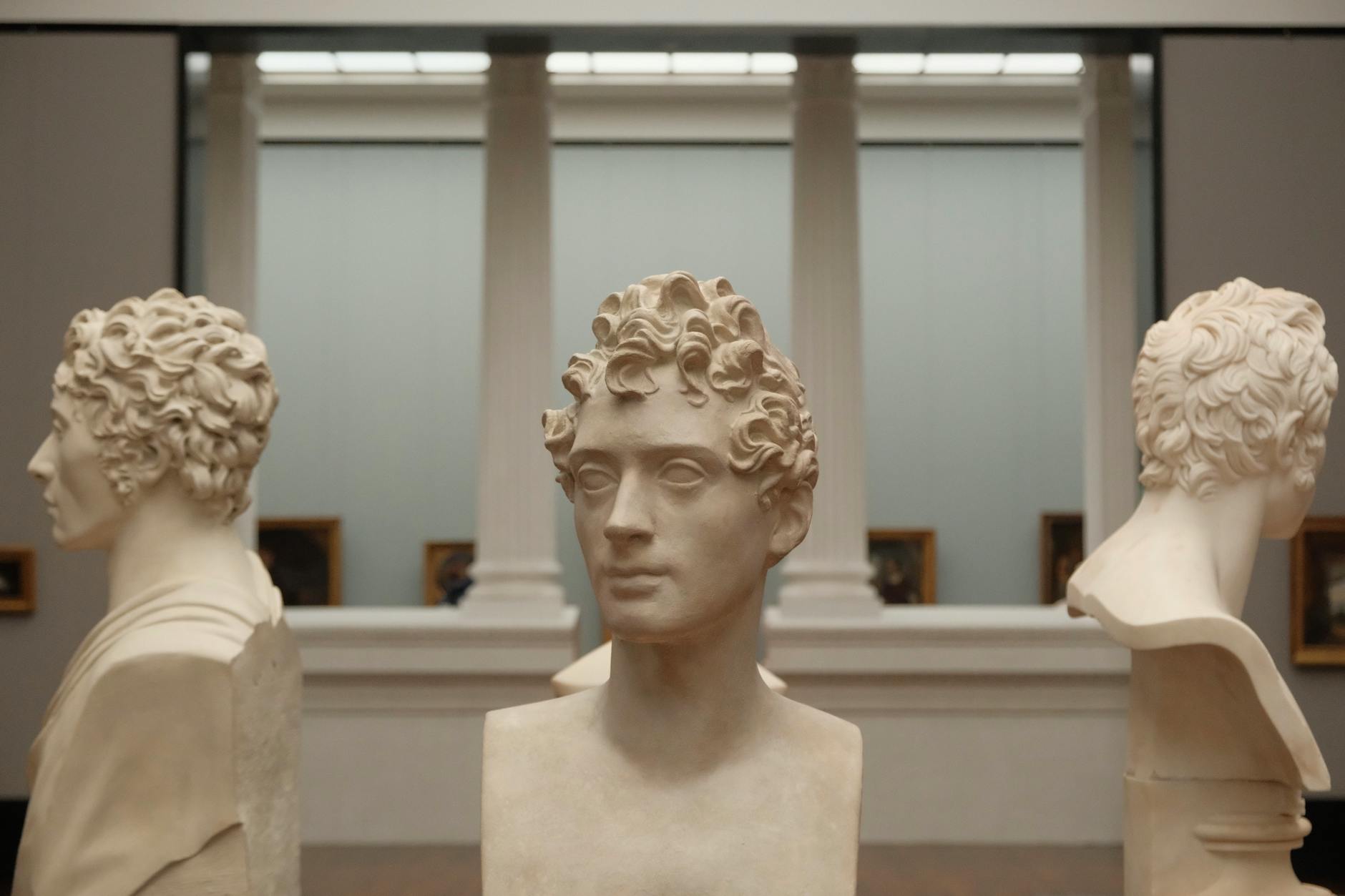 An elementary teacher pointing to a colorful painting while students observe closely during a lesson.