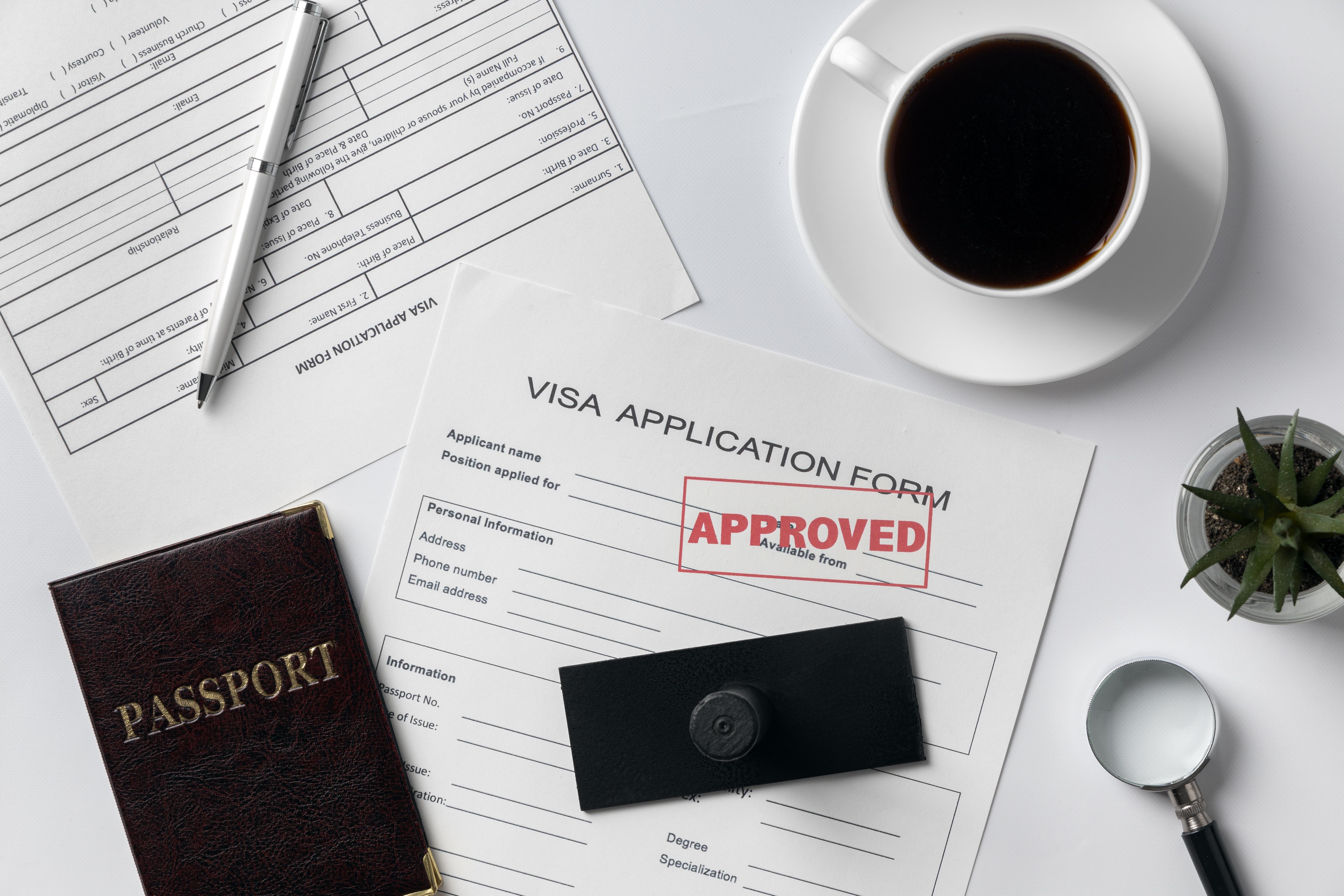 A flat lay of visa application forms with an approved stamp on it.