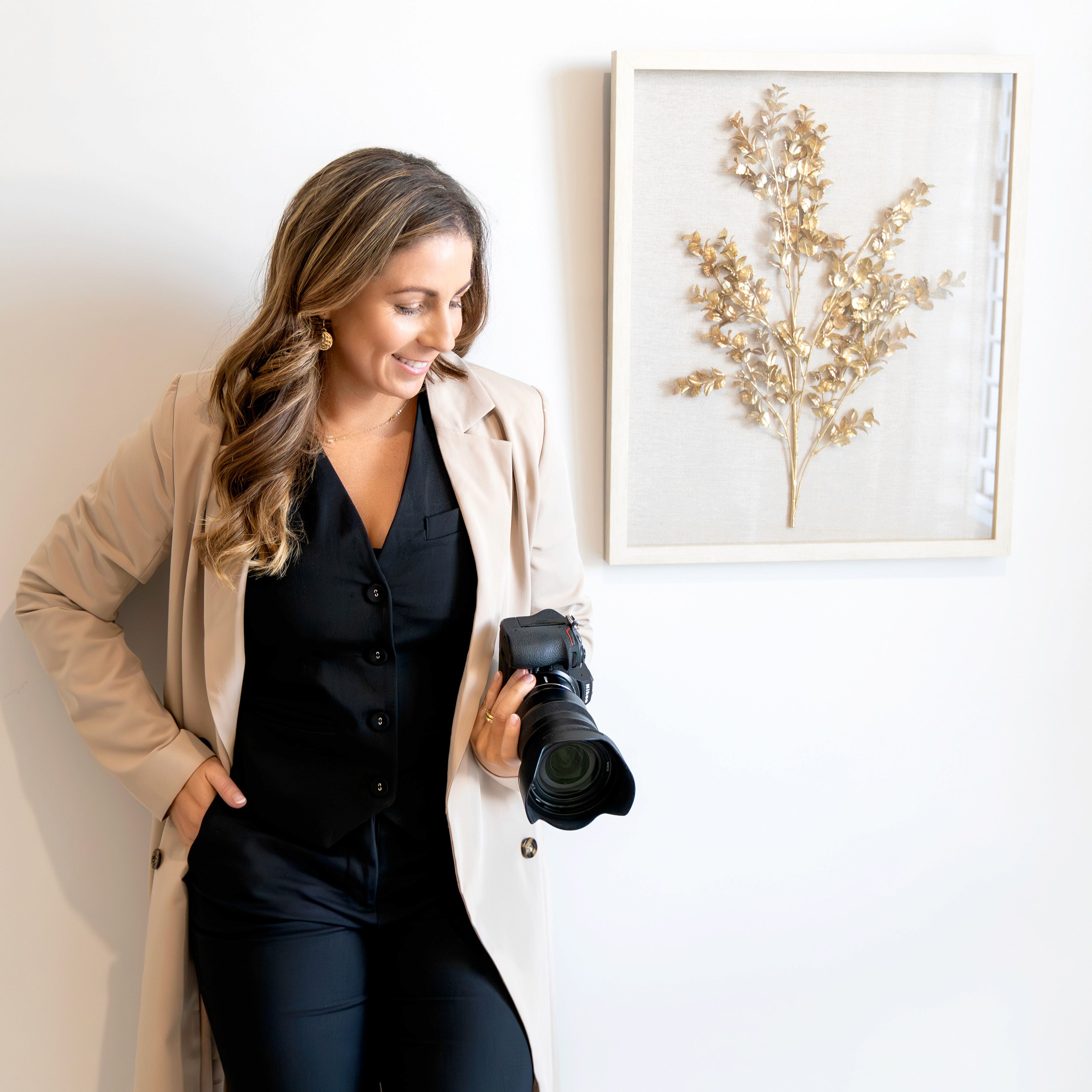 Casual studio portrait of a bearded man with curly hair in a white shirt, arms crossed, on a light gray background.