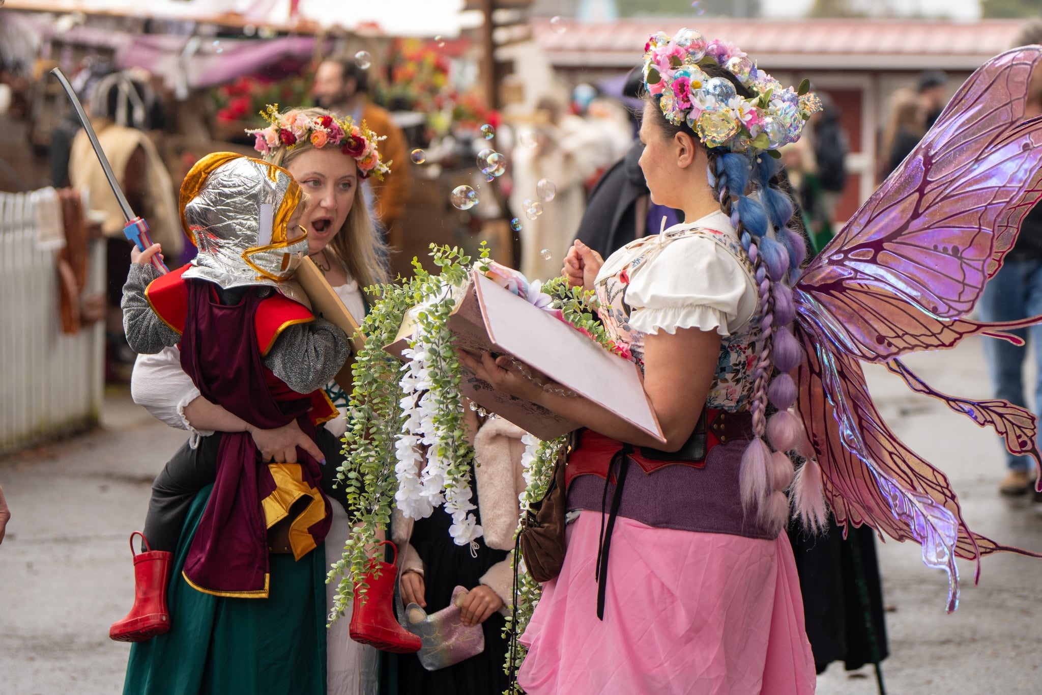 Two kids and Faire guest dressed up with book enjoying WRF