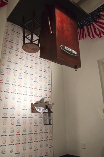 exhibition of a desk and a chair glued upside down on the ceiling