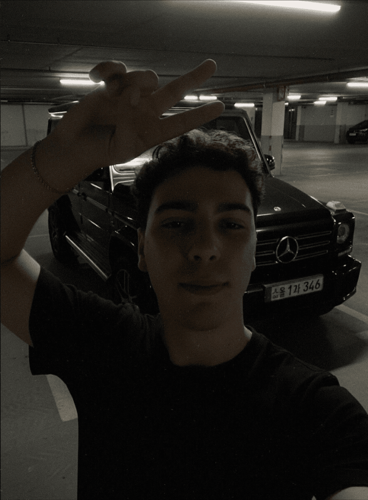 A smiling woman with her arms crossed, standing against a dark green background. She has long, dark hair.