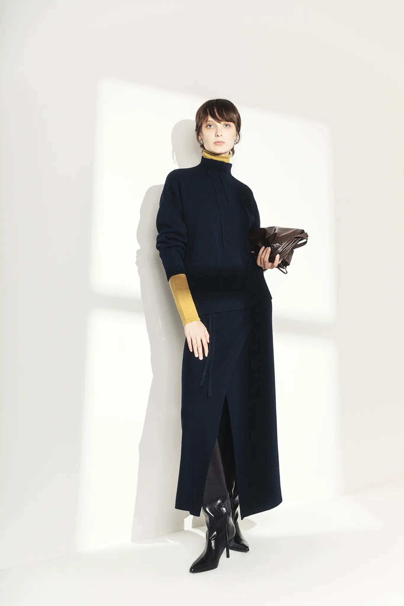 Full-length look of woman in navy cashmere turtleneck and skirt with mustard details – Aida Barni FW25/26.