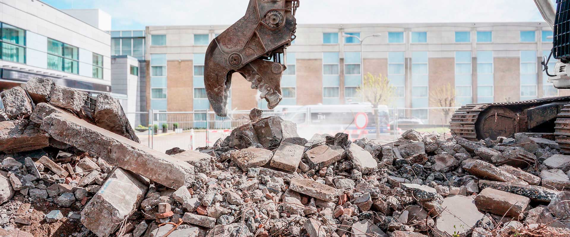 Bagger bricht Betontrümmer.