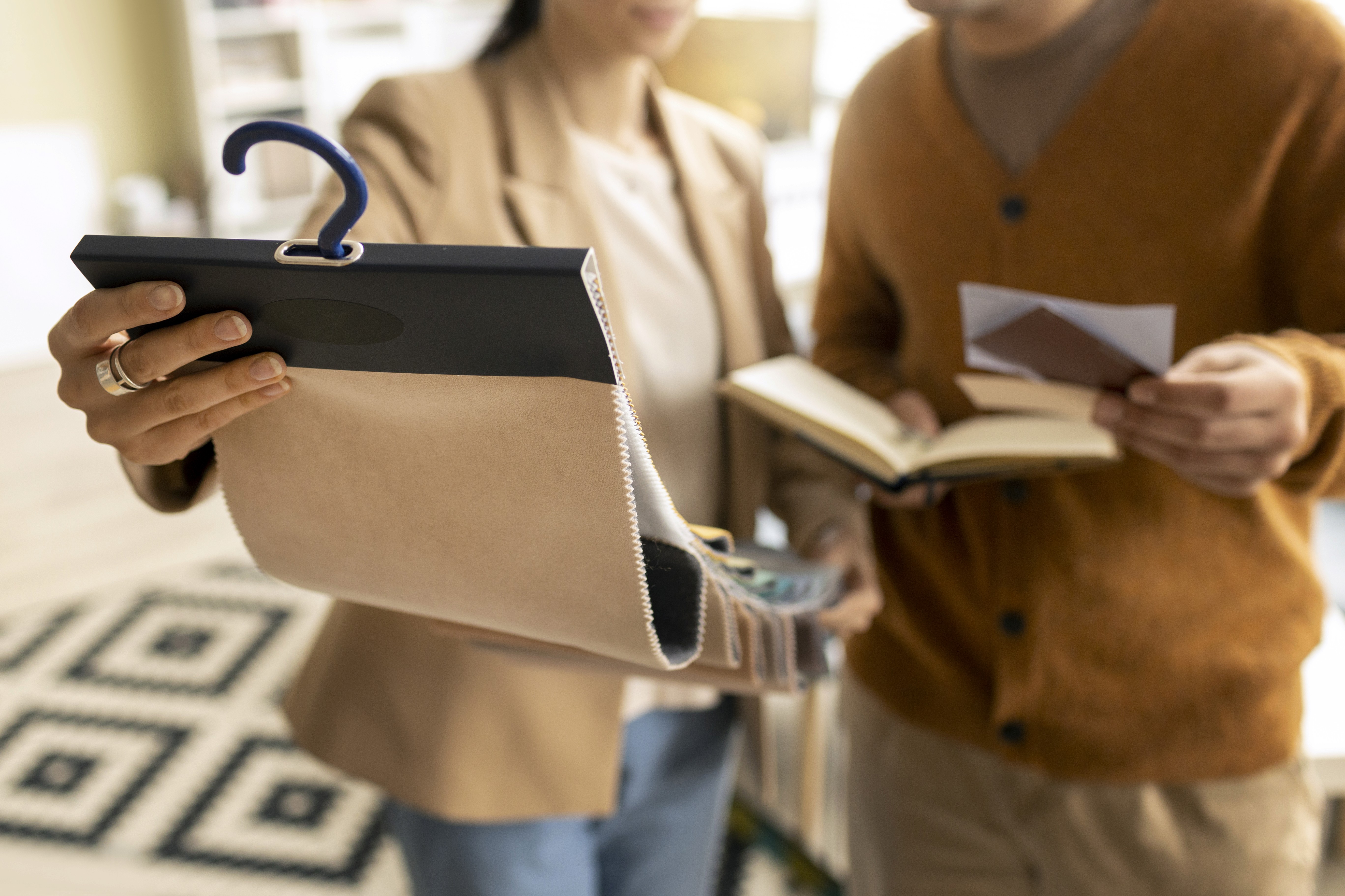 collaborating in a studio, reviewing a beige fabric swatch book and color palettes for a project