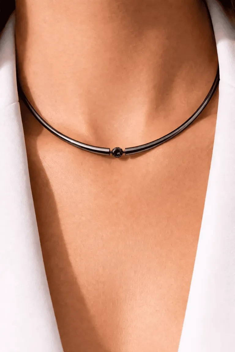 Black choker necklace on a person's neck against a white background