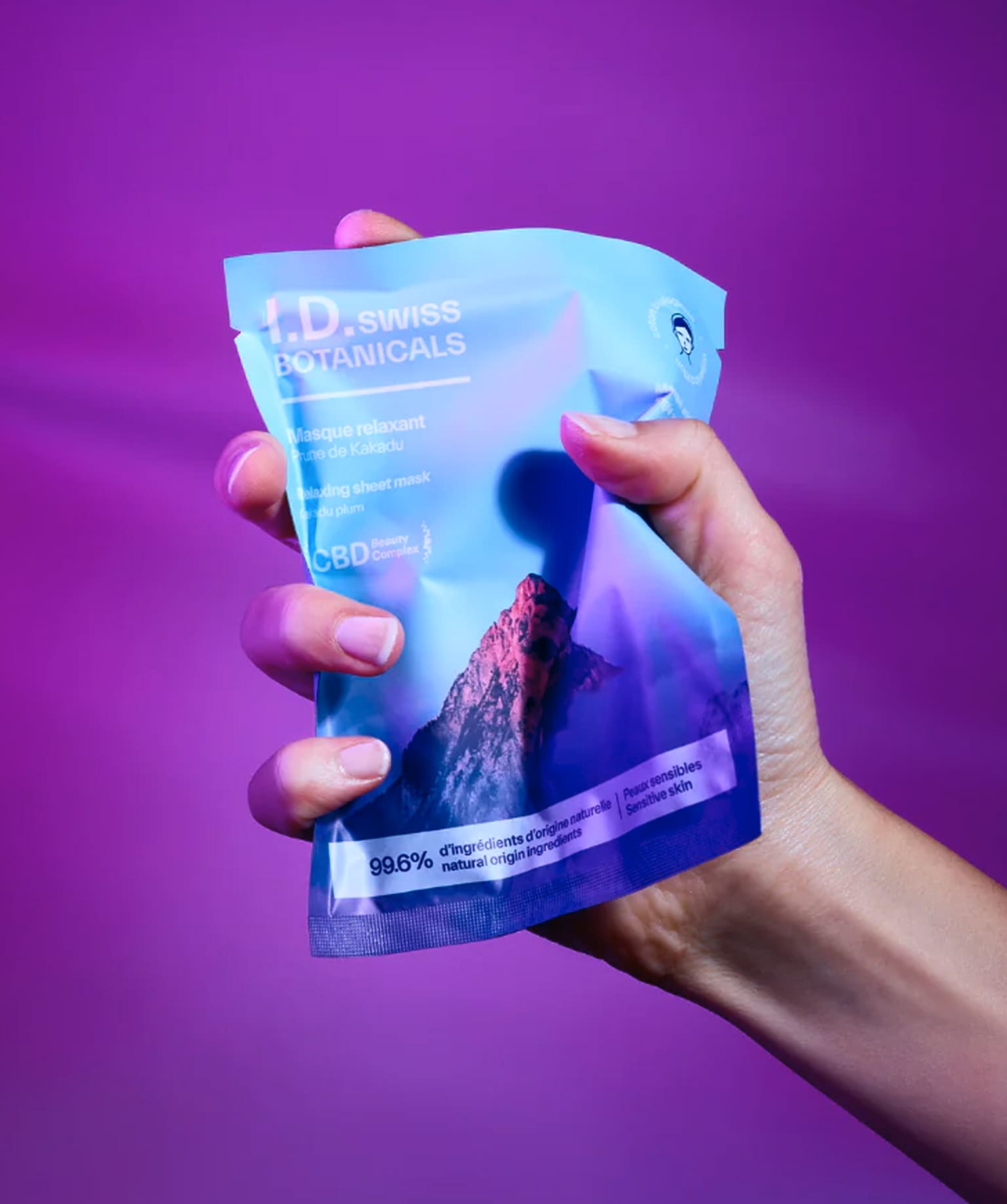 I.D. Swiss Botanicals sheet mask packaging held in hand with bold colors reflecting premium skincare branding and campaign art direction