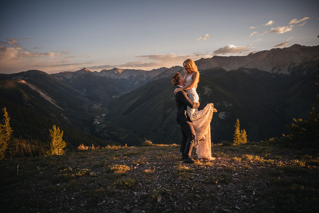 Newlyweds embracing on a mountainside at sunset