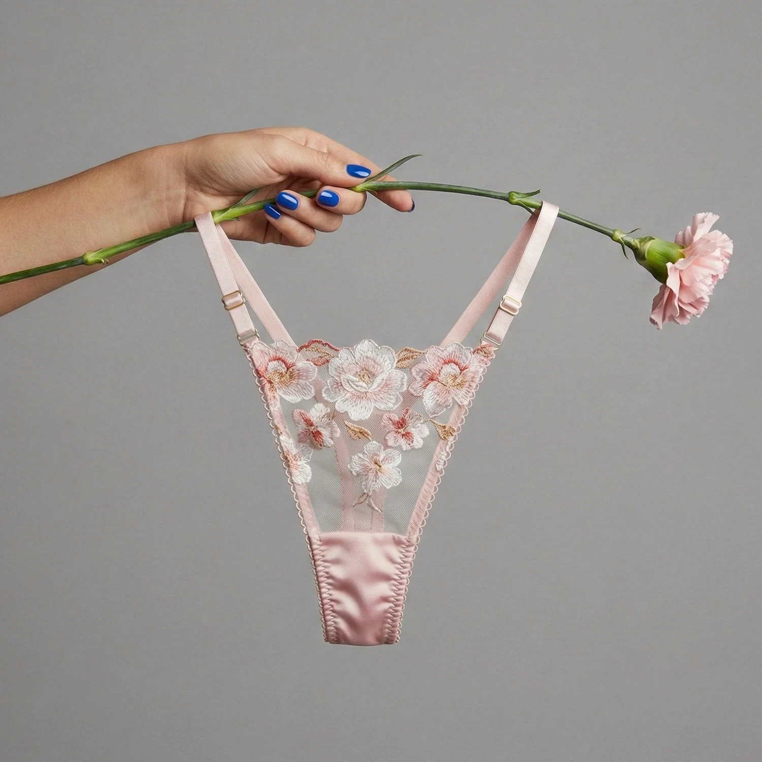 Pink embroidered lingerie held beside a carnation.