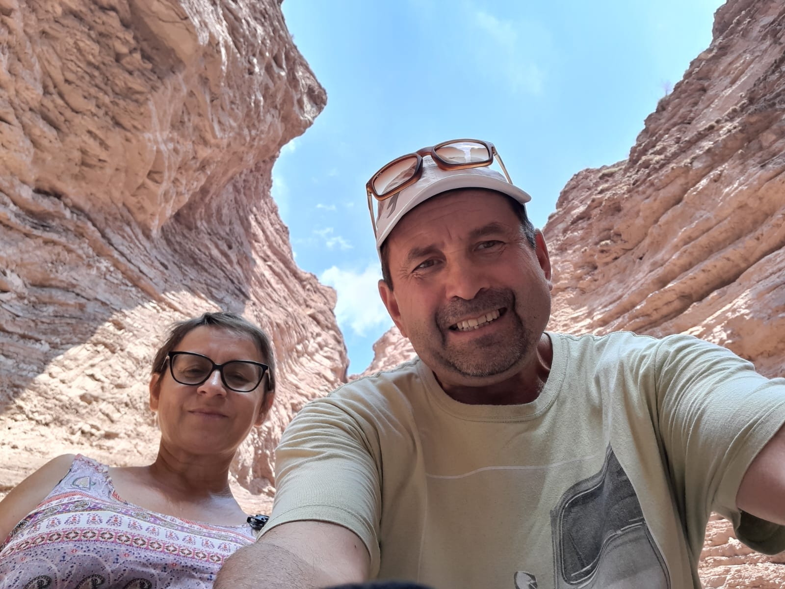Mujer sentada sobre un tronco frente a una cascada doble en un bosque frondoso de Argentina.