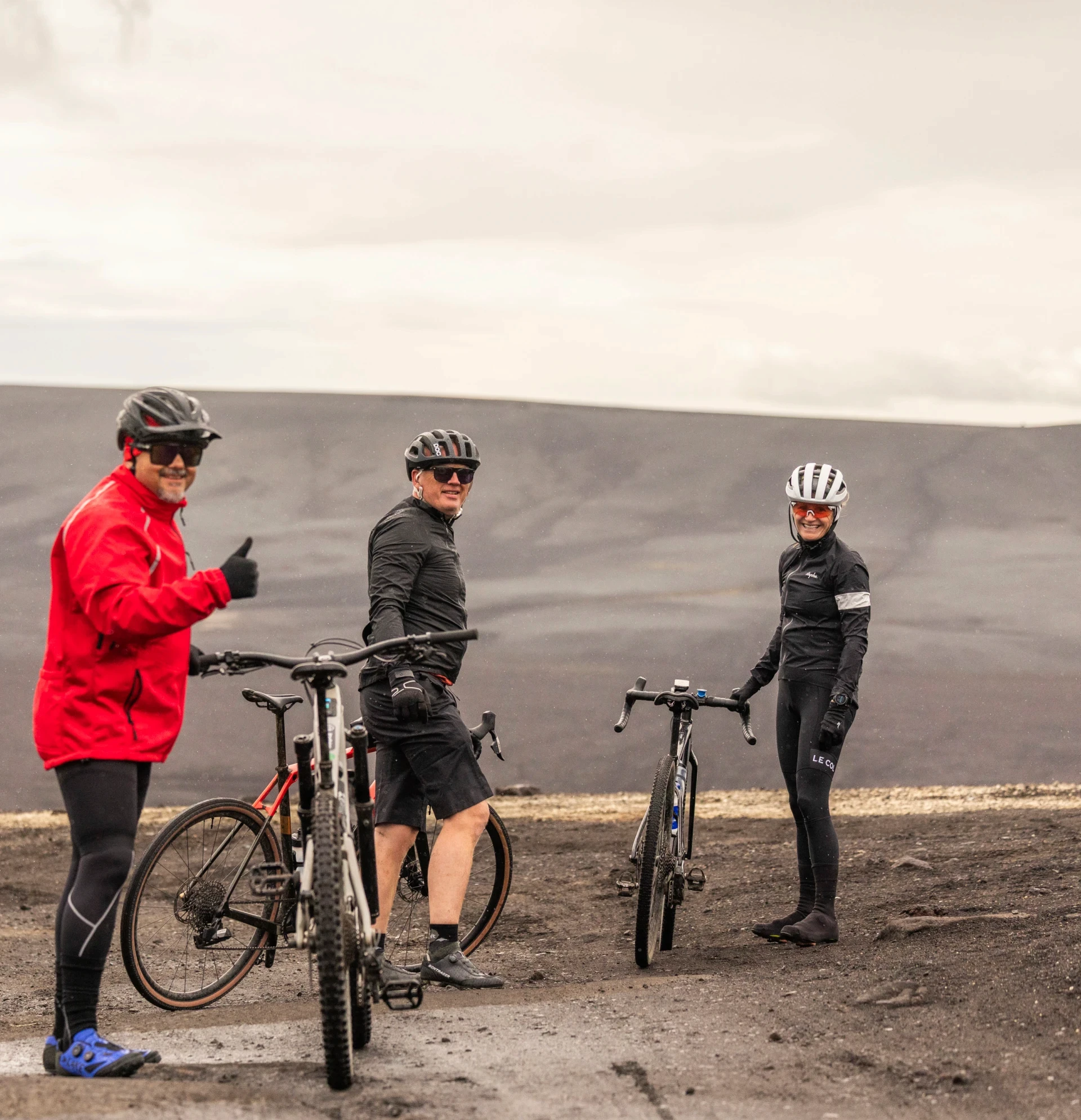 three people standing by their bikes on black sand in highland of iceland