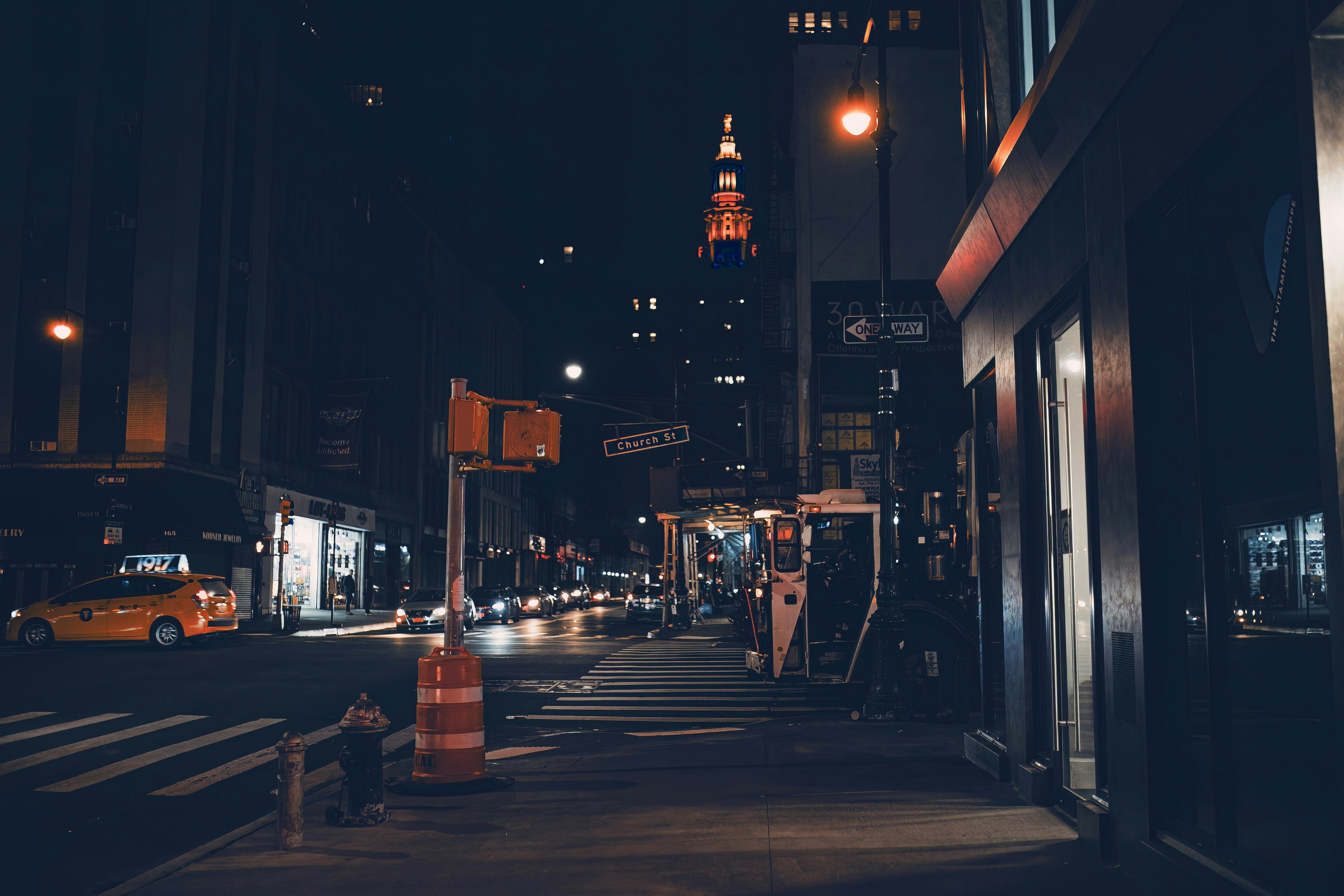 Night city street with an intersection, streetlights, and cars