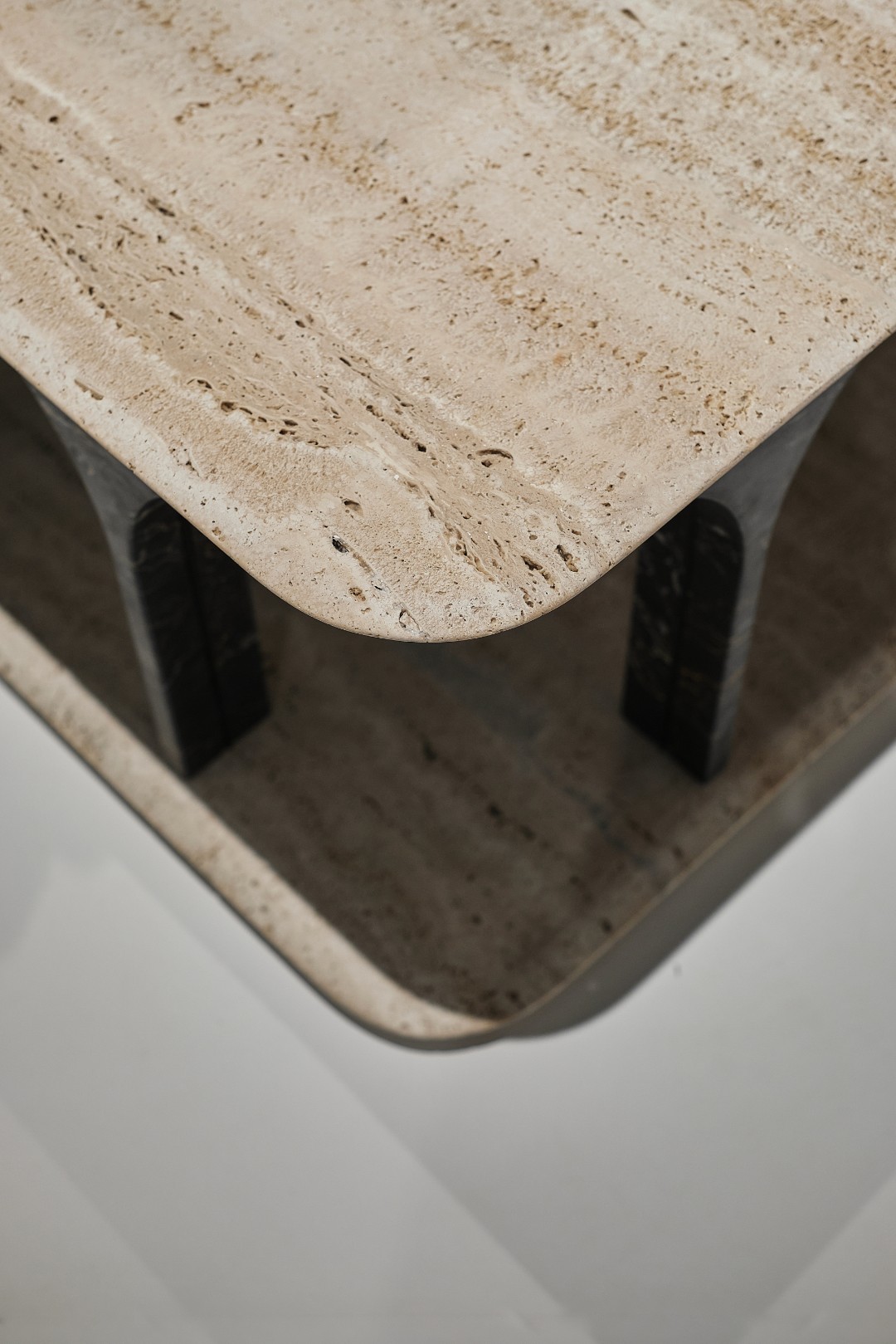 Composizione elegante su una cassettiera in legno scuro con piano in marmo nero, davanti a una parete con carta da parati testurizzata color verde salvia e azzurro sfumato. Sul piano è presente una brocca antica con erbe secche e un pezzo di corallo bianco.