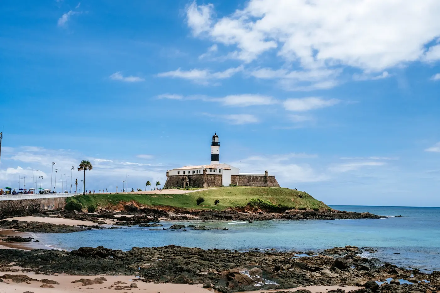 Praia tranquila em Salvador com mar azul e areia clara. Também mostra o Farol da Barra.