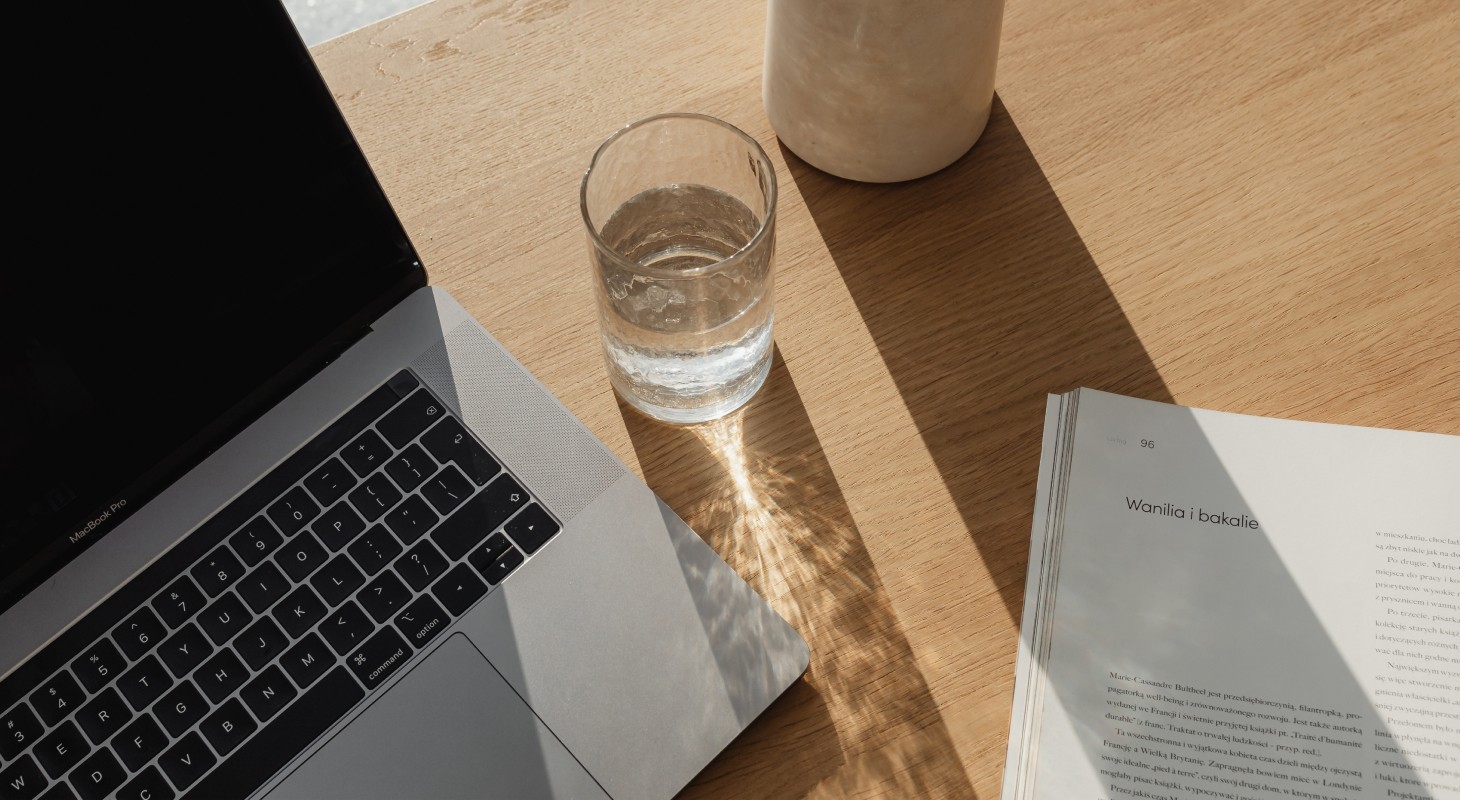 A purple luggage-style tag with a dark blue face lies on a gradient purple background. The tag displays white typed text reading “The First Productivity Framework That Won’t Make Your Eyes Roll,” along with smaller labels “Management,” “2025,” and “mklenotic.com.” A black icon with a gold letter “M” appears near the top, attached to a tan cord.