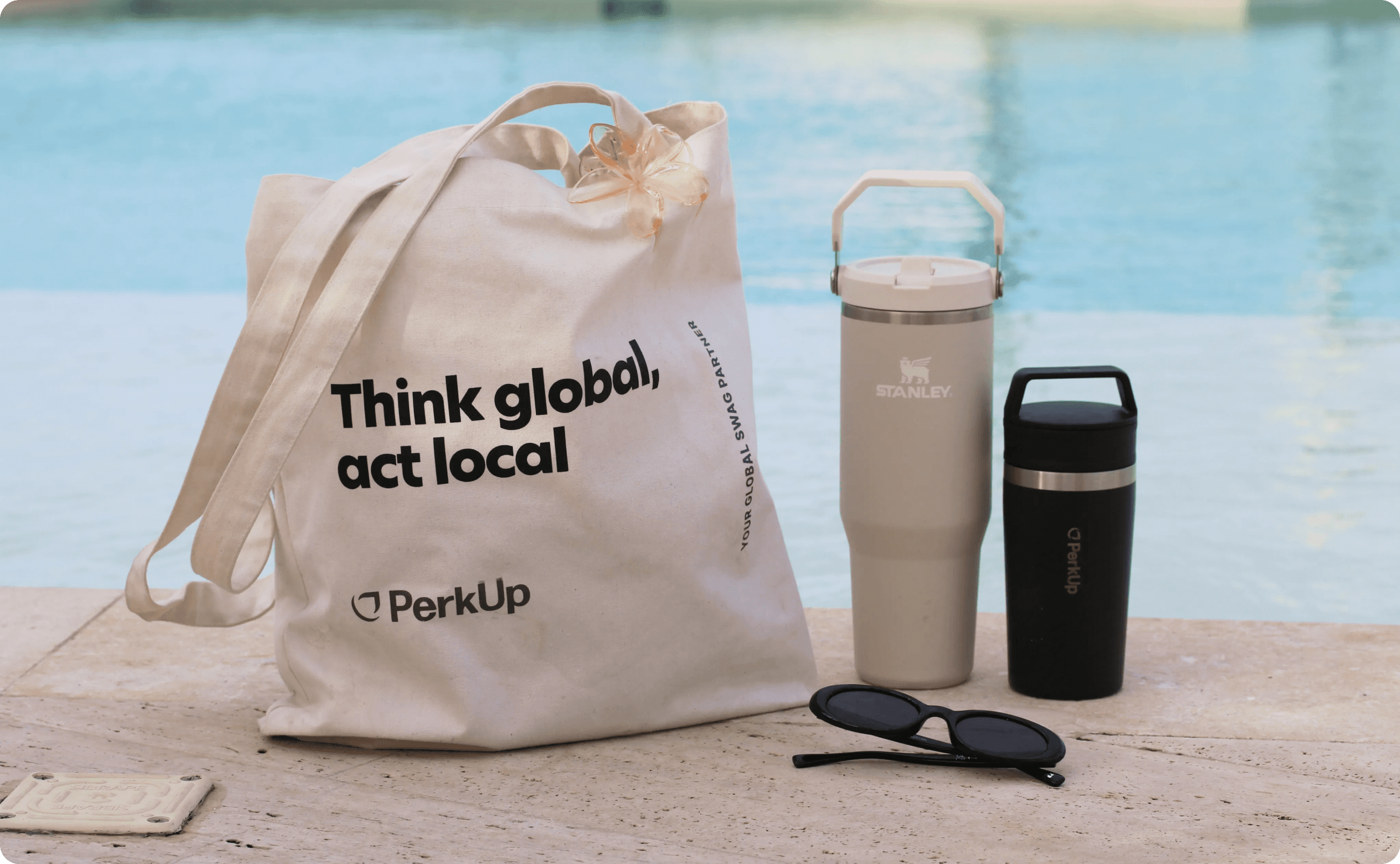A tote ba, a Stanley tumbler, a coffee tumbler, and sunglasses.