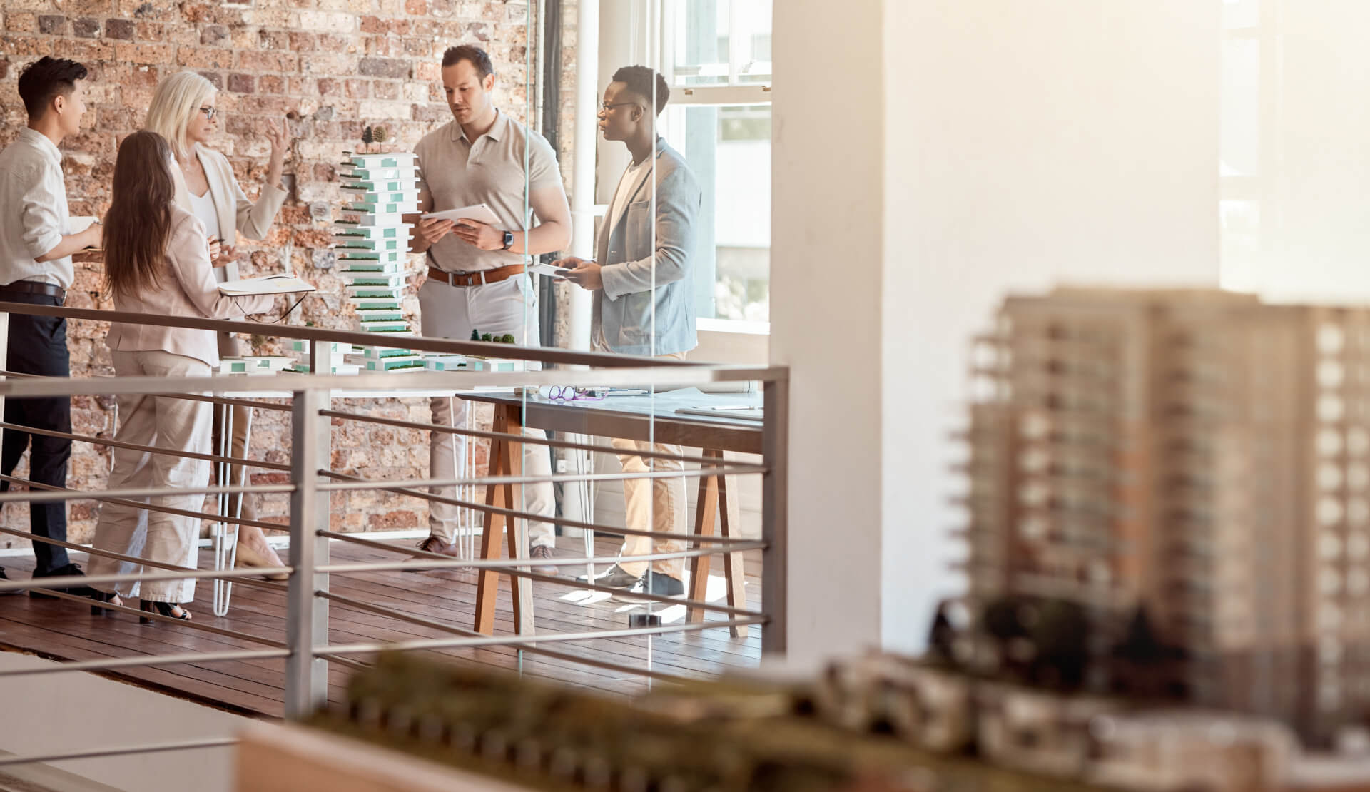 A group of professionals discusses ideas in a modern workspace with large windows and wooden accents.