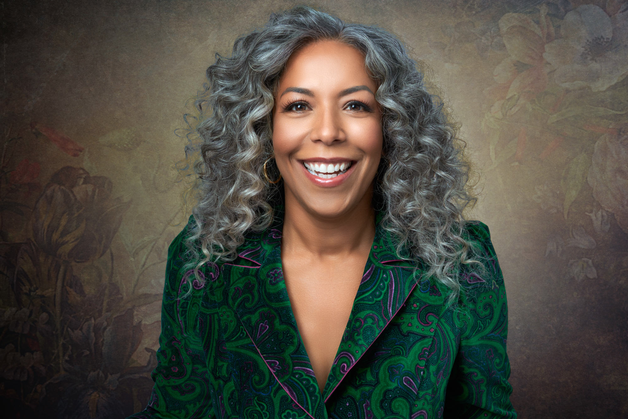 Vibrant studio headshot of woman with long silver curly hair
