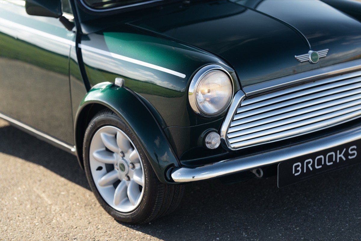 Close-up of a classic green Mini car showcasing its front grille and shiny alloy wheels.