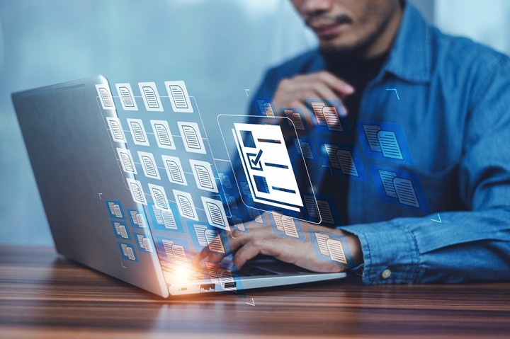 Professional using a laptop with digital document icons overlaid, representing the management and maintenance of company records