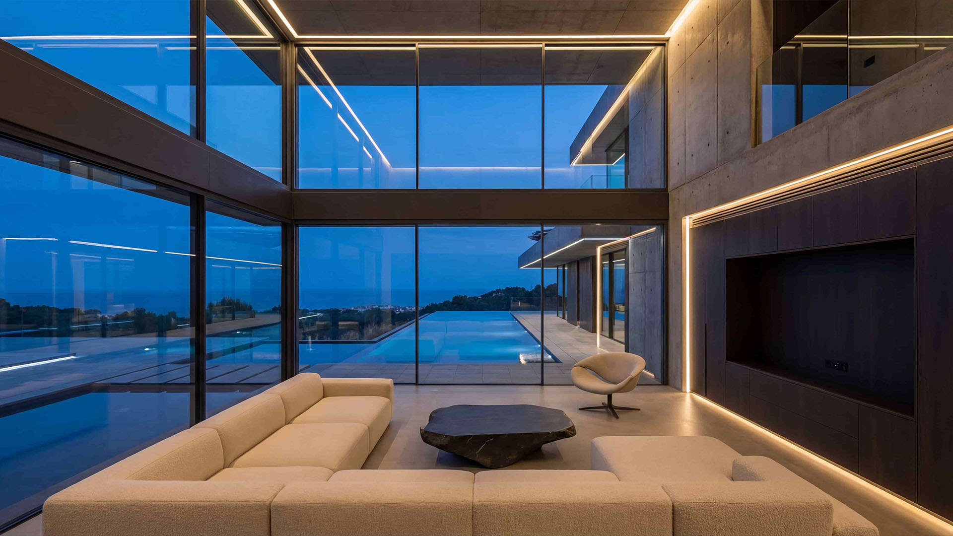 Modern luxury villa interior with open-plan living area, floor-to-ceiling windows, and infinity pool view in Marbella