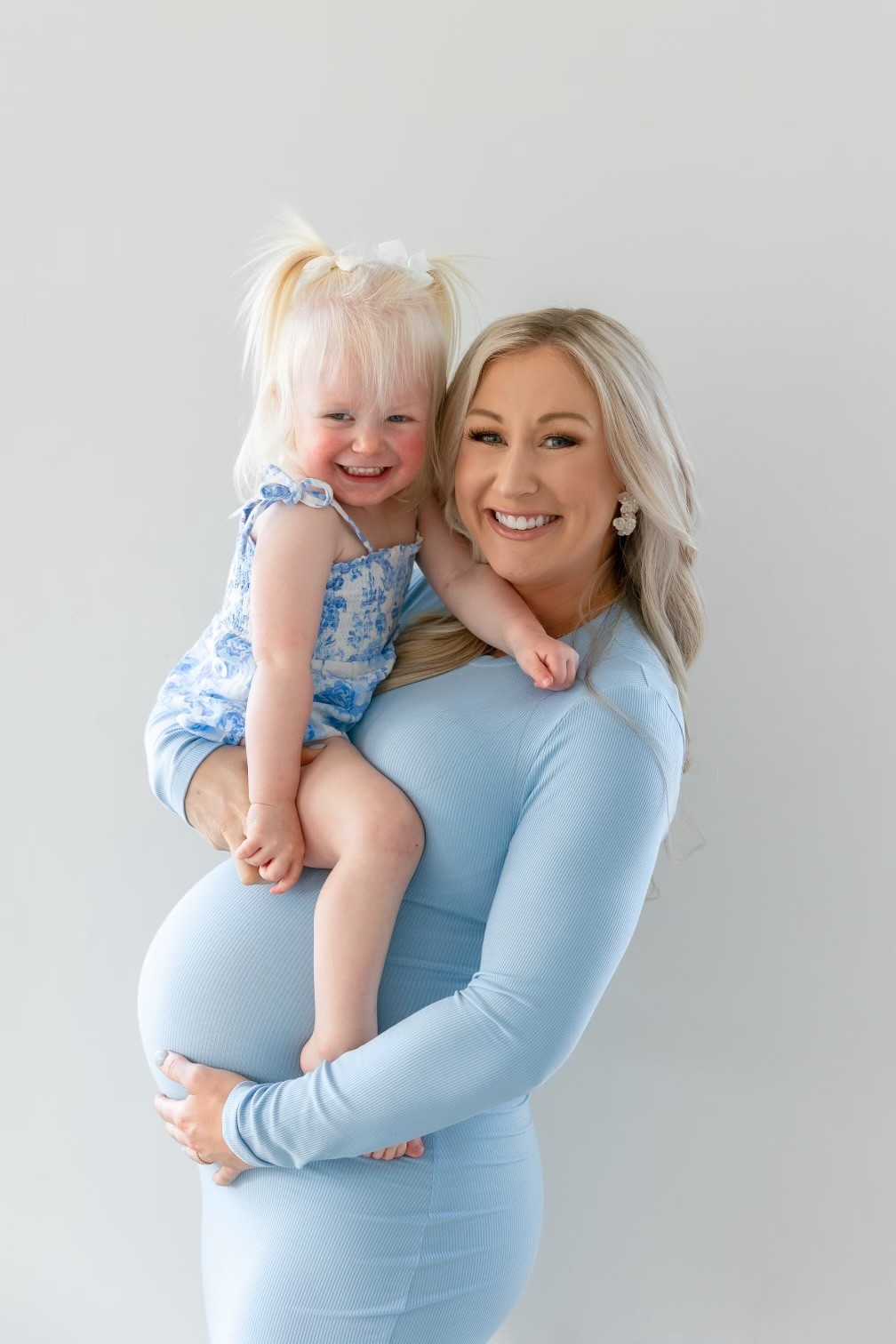 happy pregnant mother holding older daughter