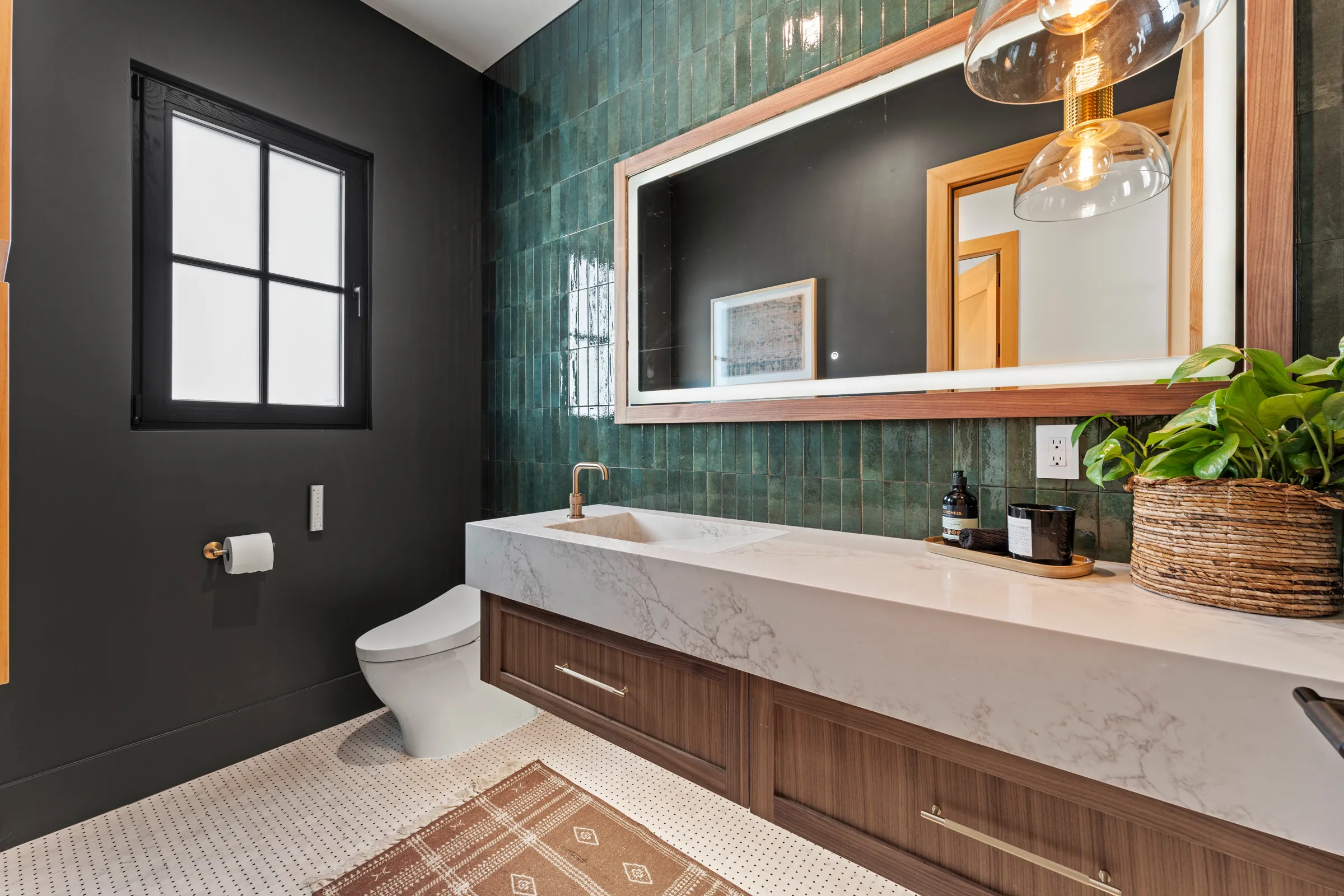 aBathroom with green tile wall, floating vanity and backlit mirror built by ERC