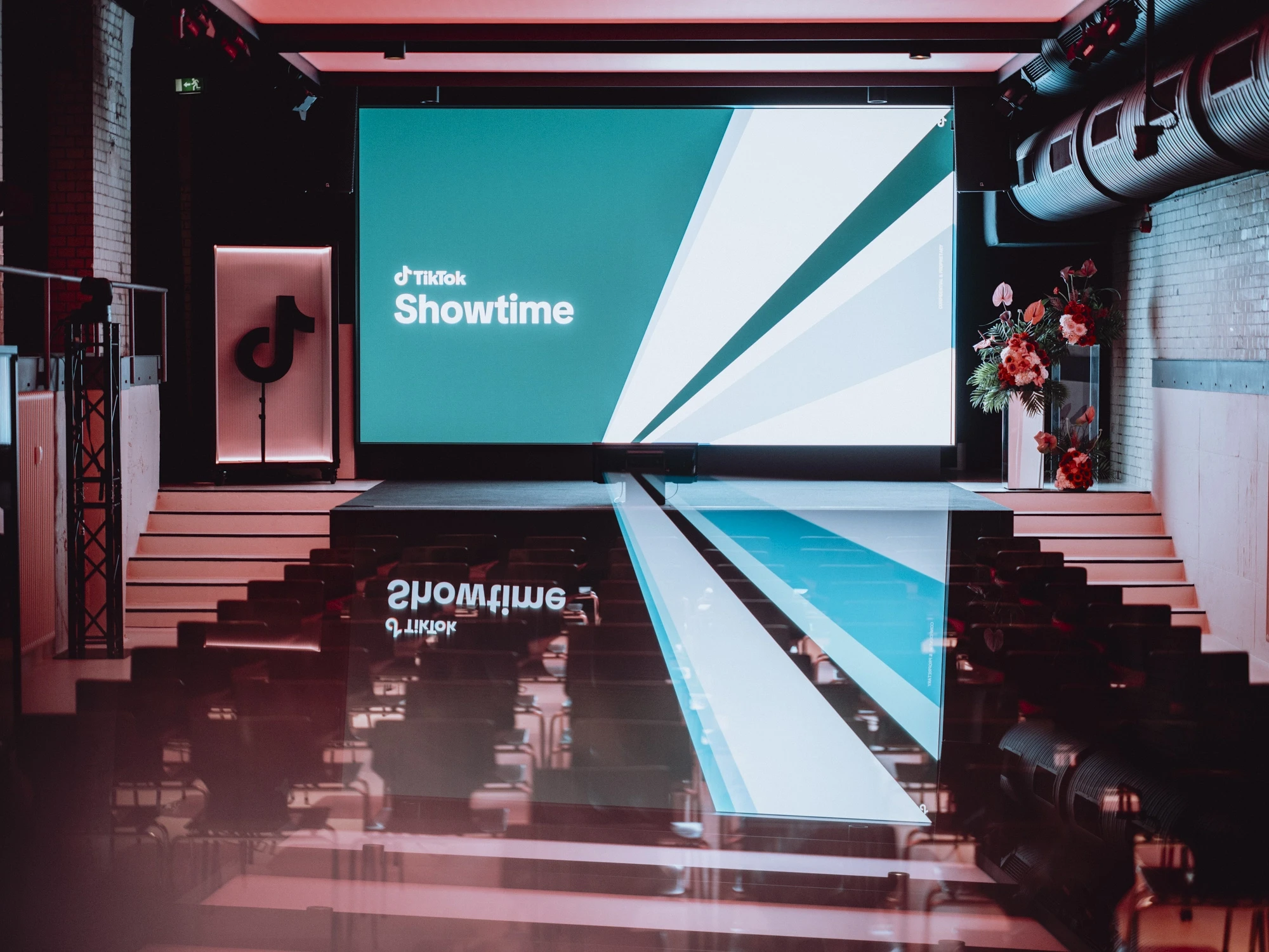Cinema-style hall with TikTok Showtime screen, mirrored runway, stairs and flower column.