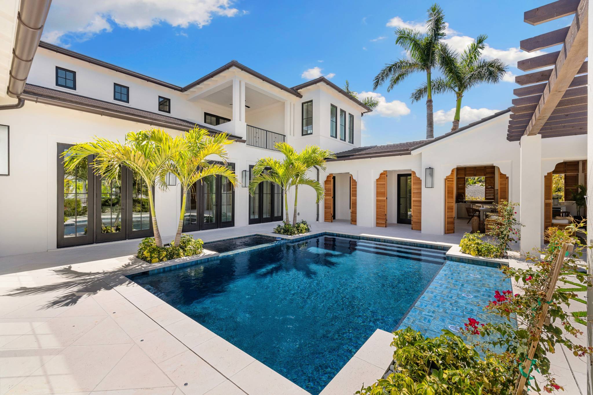 a large modern courtyard with a pool in the foreground and blue sky with palmtrees in the background